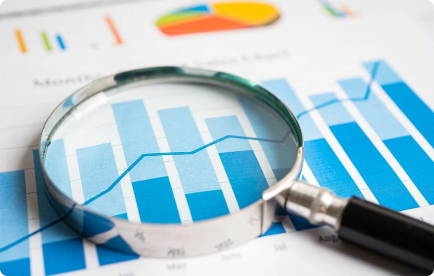 Lupa resalta barras y línea en informe financiero, simbolizando análisis de datos tributarios, sobre fondo de gráficos.